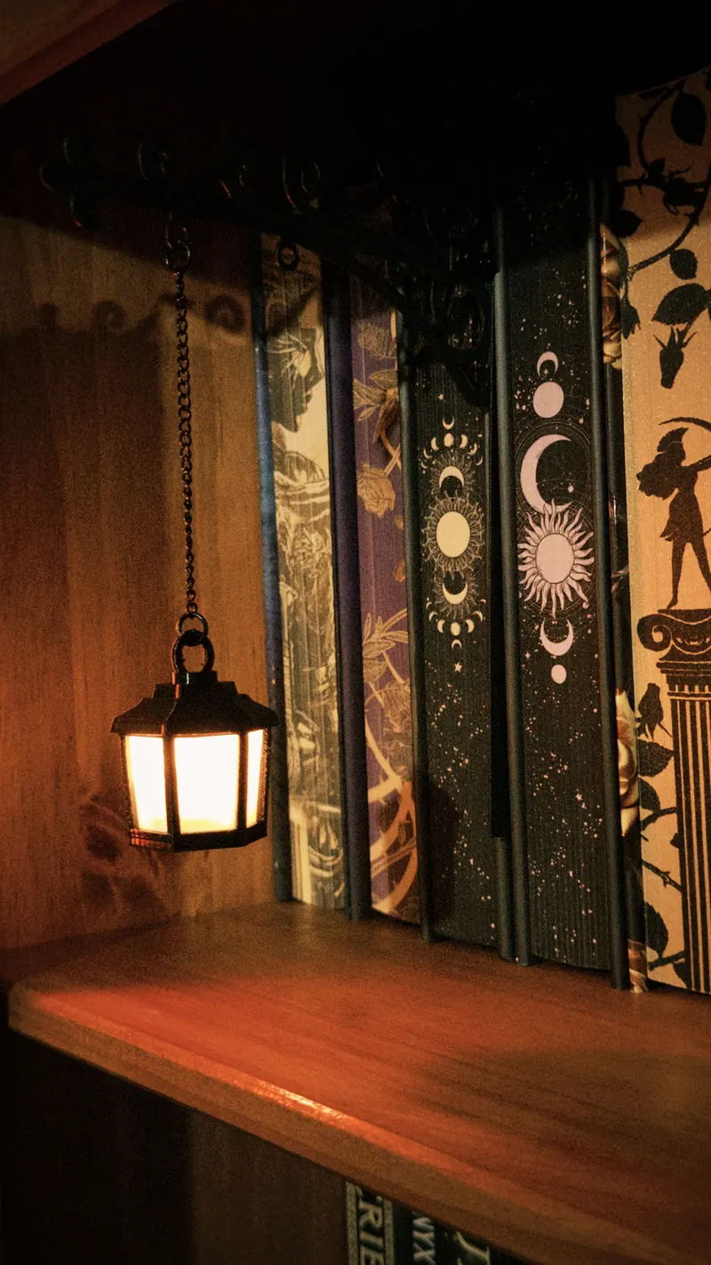 Lanterna acesa ao lado de lombadas ilustradas de livros de fantasia na estante
